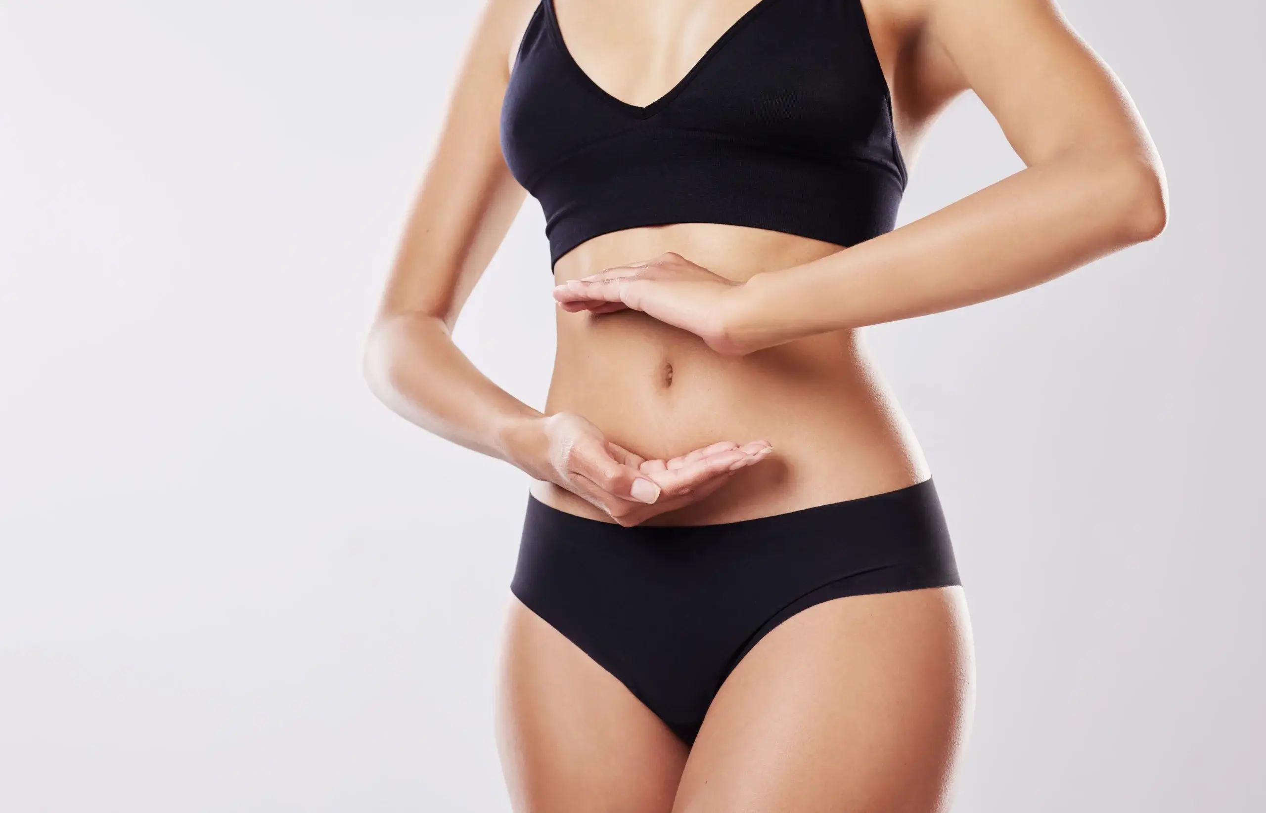 fit-woman-holding-her-hands-over-her-flat-stomach-2026-05-21-16-14-35-utc